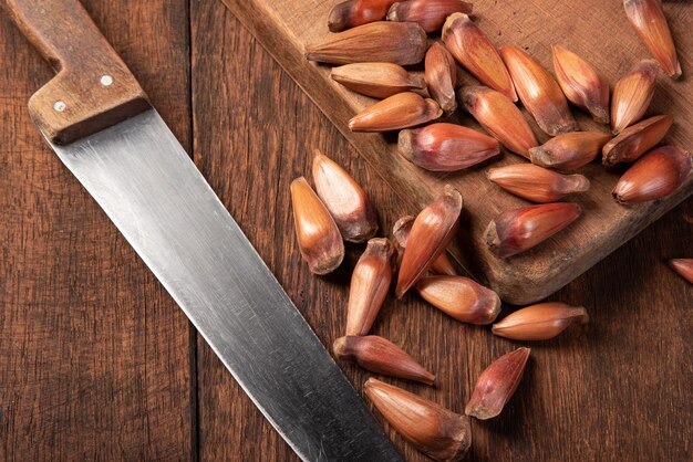 Pinhao, pinion, pine fruit, Brazilian Araucaria tree, on rustic wood with a knife, top view.