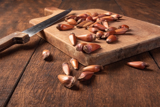 Pinhao, pinion, pine fruit, Brazilian Araucaria tree, on rustic wood with a knife