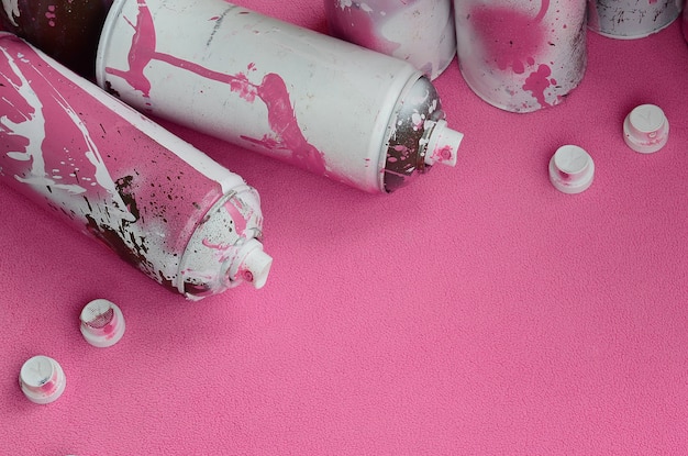  pink aerosol spray cans and nozzles with paint drips lies on a blanket