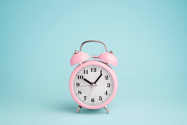 Photo pink alarm clock on blue