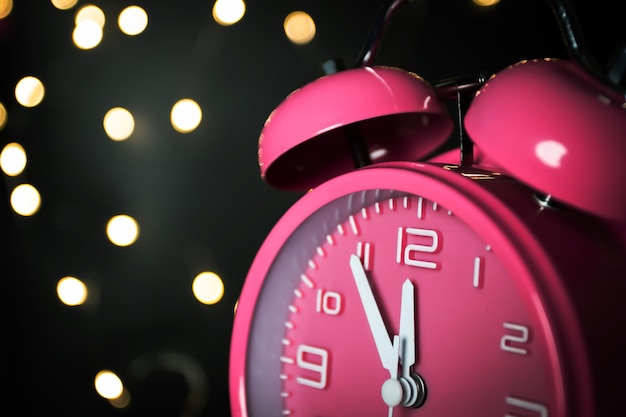 Sveglia rosa con sfondo bokeh orologio per il conto alla rovescia per festeggiare il felice anno nuovo