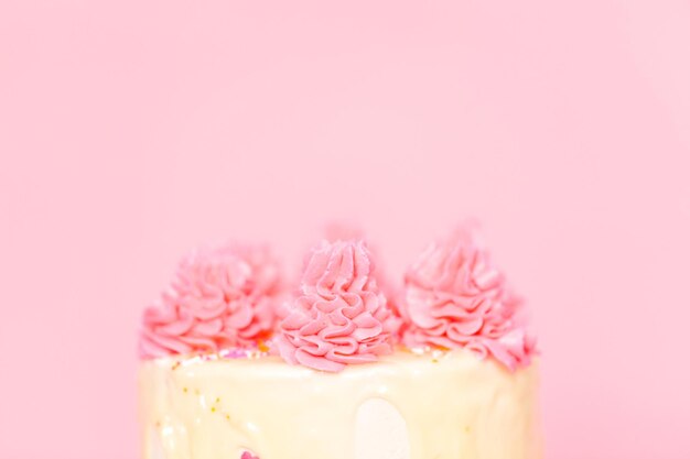 写真 ピンクのスプリンクルとホワイトチョコレートのガナッシュドリップが入ったピンクと白のバタークリームクリームケーキ。