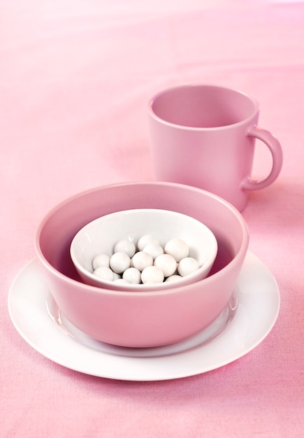 사진 분홍색 천으로 표면에 설탕 dragees와 분홍색과 흰색 그릇