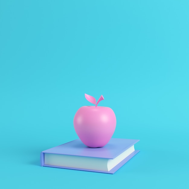 Pink apple on a book on bright blue background