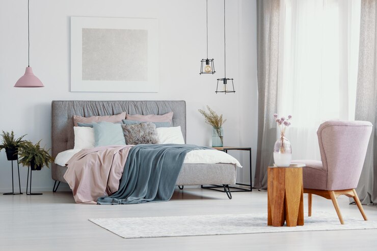 Photo pink armchair next to wooden stool in bedroom interior with poster above grey bed real photo