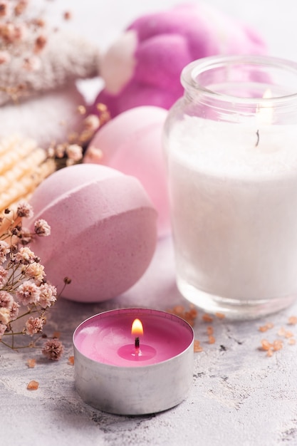 Pink aroma bath bombs in SPA arrengement with dry flowers and lit candle