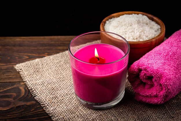 Розовое ароматное полотенце свечи и соль на деревянном фоне
