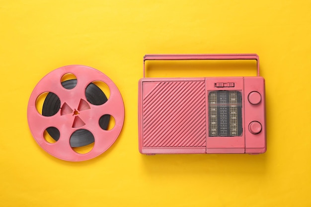 Pink audio reel and cool radio receiver on yellow background\
musical concept top view flat lay