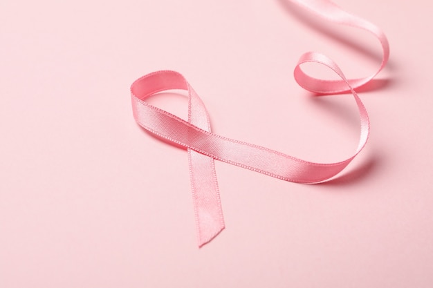 Pink awareness ribbon on pink background