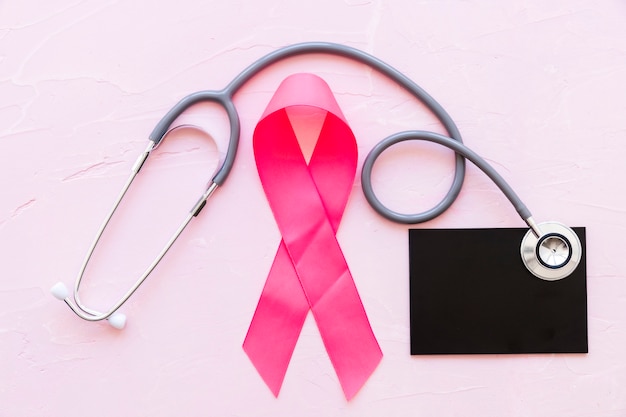 Pink awareness ribbons with stethoscope over slate on pink background