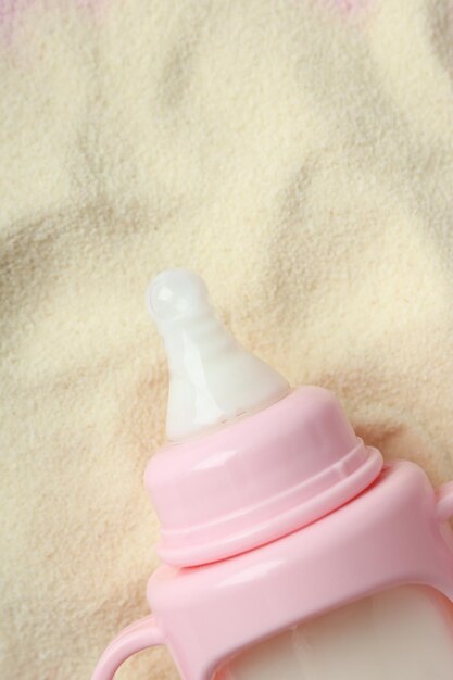 Photo pink baby bottle on powdered milk background