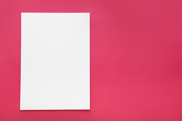 Photo on a pink background a white sheet of paper top view template blank for design