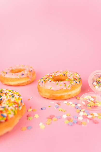 Photo a pink background with donuts and sprinkles on it