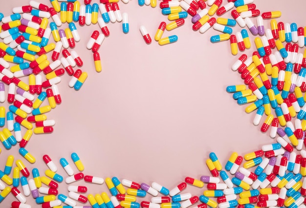 A pink background with a lot of pills and a heart in the middle