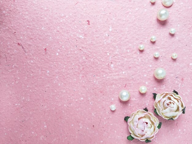 Pink background with pearls and roses Top view with copy space