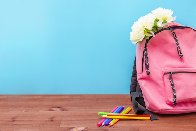 Photo in a pink backpack flowers, colored pencils on the table
