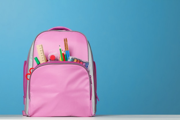 Pink backpack with office supplies on the table.