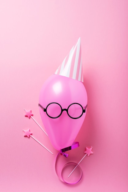 Pink balloon with party hat and magic wands