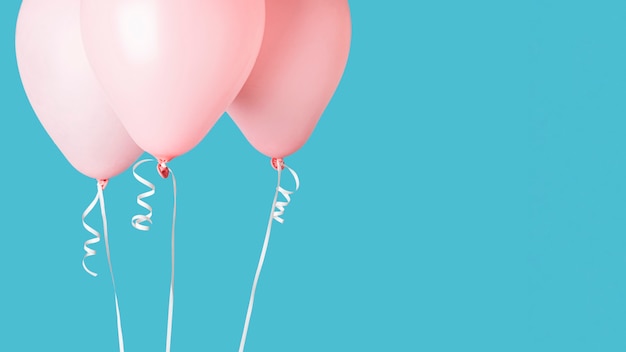 Photo pink balloons with ribbons on blue background