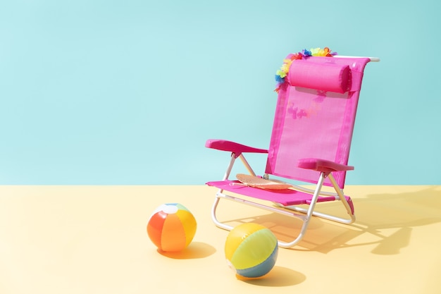 A pink beach chair with two multicolored beach balls