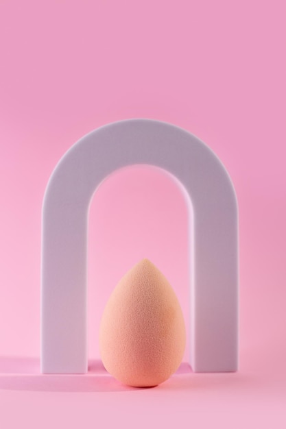 Pink beauty blender isolated on pink background with arch Pink blending sponge for makeup Minimal