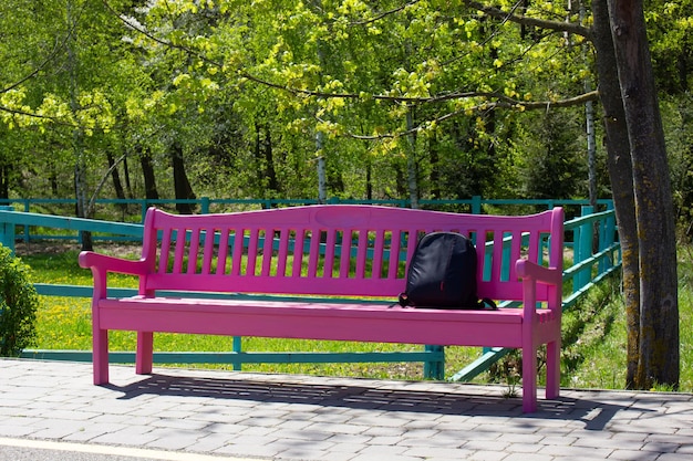 A pink bench in the park near the path Rubzak on the bench under the tree