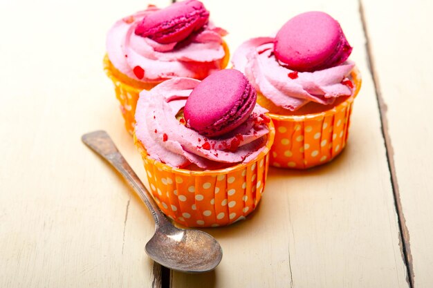 Photo pink berry cream cupcake with macaroon on top