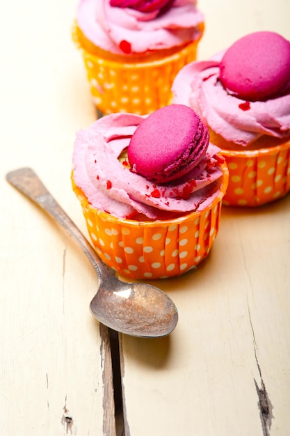 Foto cupcake a crema di bacche rosa con maccheroni in cima