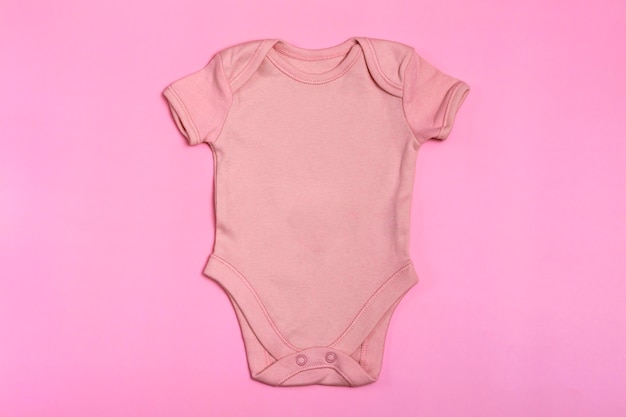 Pink blank baby bodysuit template, mock up close-up on pink background. Baby bodysuit, jumpsuit for newborns. View from above