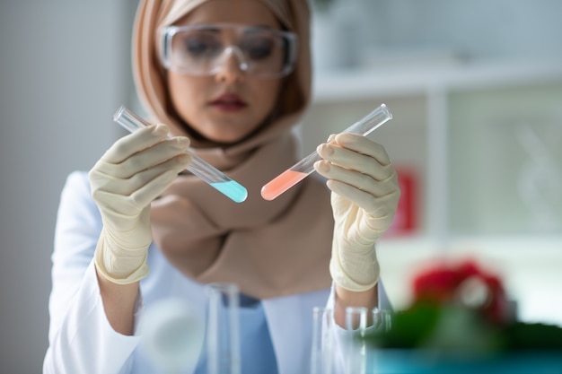 Pink and blue. Close up of female chemist holding test tubes with pink and blue chemical agents