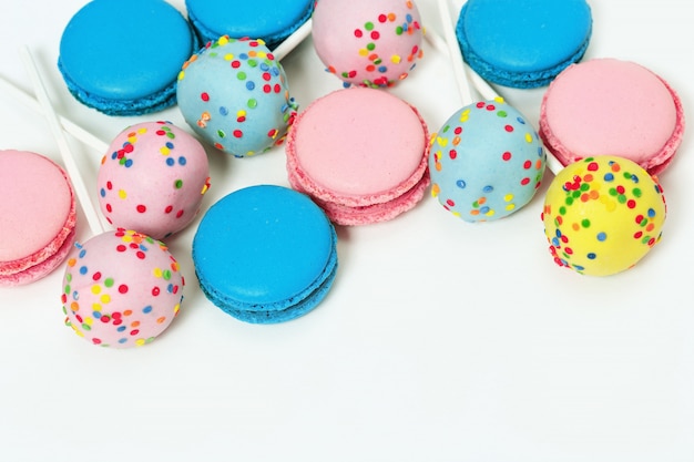 Pink and blue macaroons and cake pops on white background with copy space. Assorted cookies.