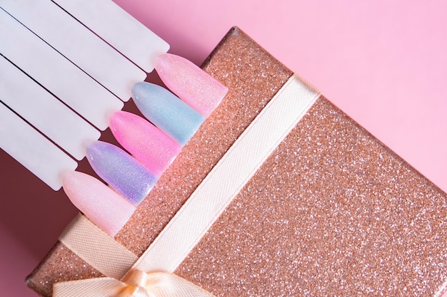 A pink and blue nail polish set with a bow on a pink background.