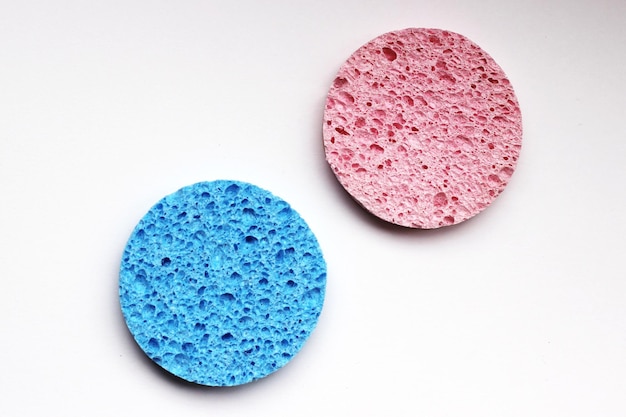 Pink and blue round textured cosmetic sponges on white background