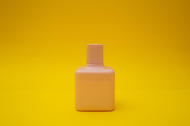 黄色の背景に香水のピンクのボトル