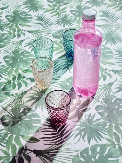 Pink bottle with colorful water glasses