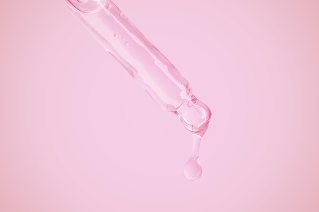 A pink bottle with a drop of liquid being poured into it.