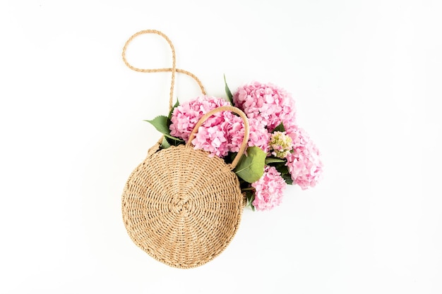 Pink bouquet of hydrangea in a straw bag on white background