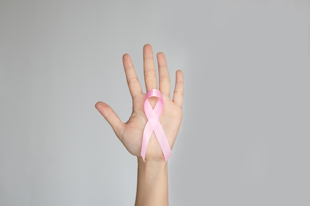 Pink bow ribbon in human hand to encourage breast cancer patient Breast cancer campaign in October month