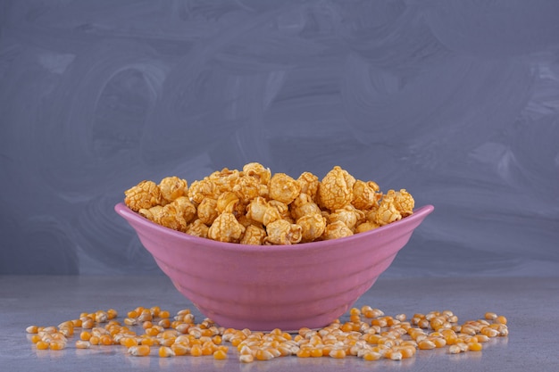 Pink bowl of salty popcorn on stone surface