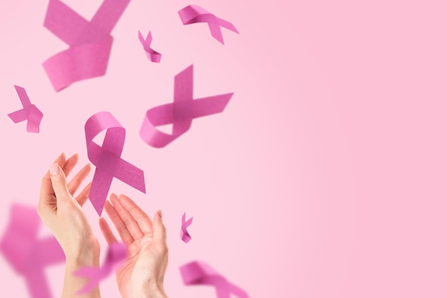 Foto pink breast cancer awareness ribbon vrouwelijke hand die een roze lint vasthoudt vliegend symbool van de strijd tegen borstkanker breast cancer awareness en oktober pink day world cancer day top view mock up