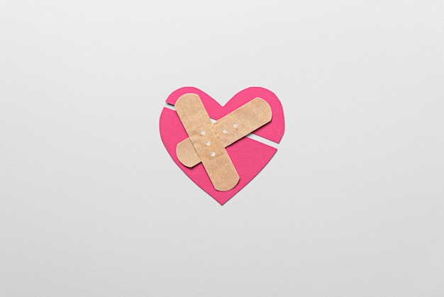 Pink broken heart with band aids top view