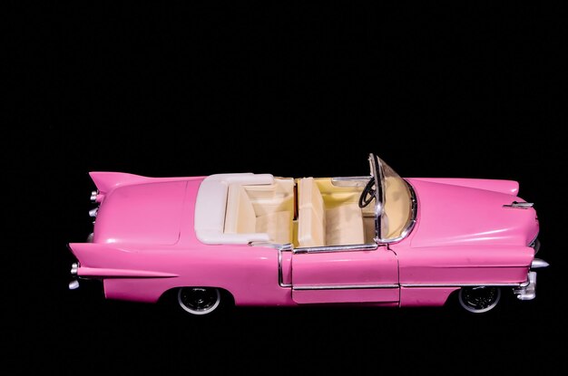 Foto modello di auto giocattolo caddilac rosa isolato su sfondo nero