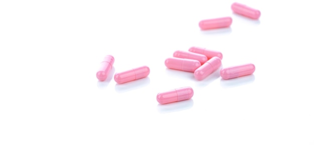 Pink capsule pills on white background Pharmaceutical industry Vitamins minerals and supplement