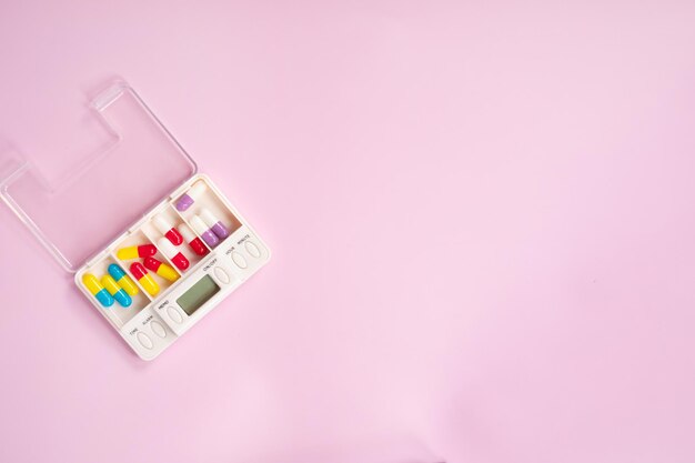 A pink case with a small set of medicine and a timer.