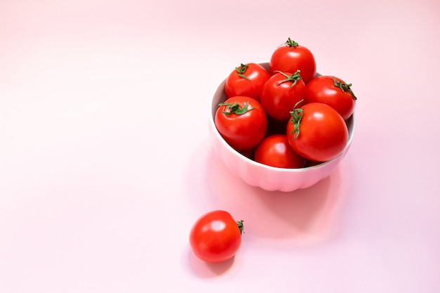 Pink ceramic bowl with ripe red tomatoes on a pink background. Healthy Diet Vitamins Bio Foods