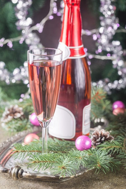 Champagne rosato in un bicchiere e decorazioni natalizie