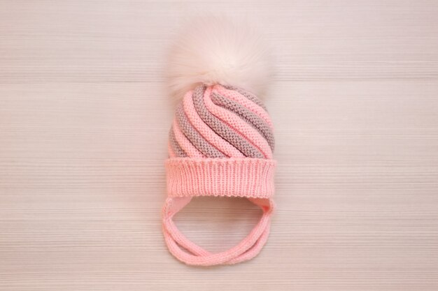 Photo pink children's knitted wool hat with a pompom, on a white background