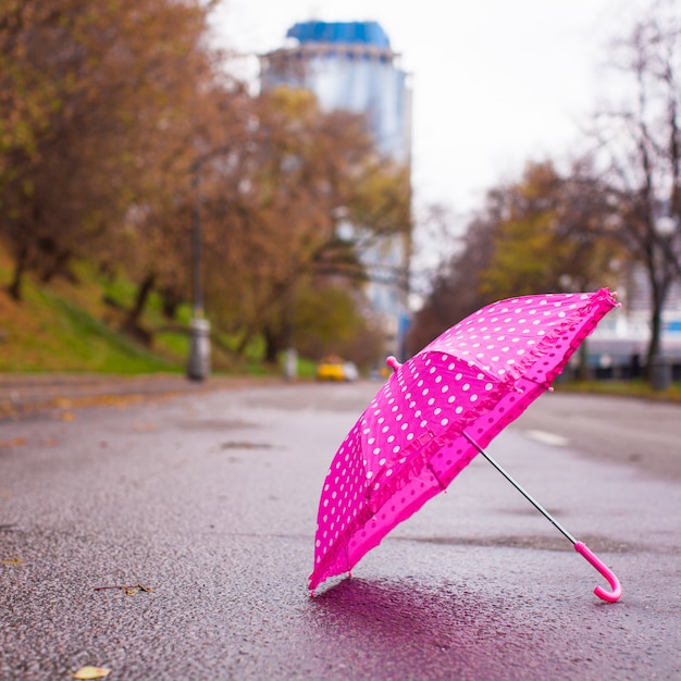 Pink children's umbrella on the wet asphalt outdoors