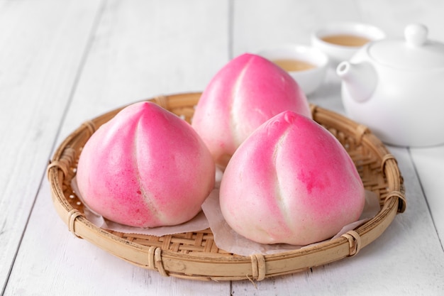 Pink Chinese peach birthday bun food named Longevity peach shoutao on white table background.