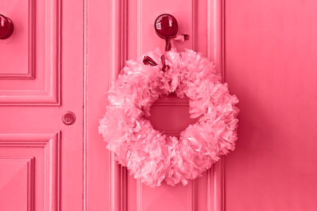 Pink Christmas wreath of plastic bags on front door Christmas decoration concept Image toned in color of the year 2023 viva magenta
